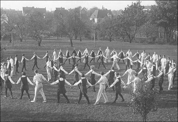 Kvinder og mænd i samlet dans i haven ved instituttet